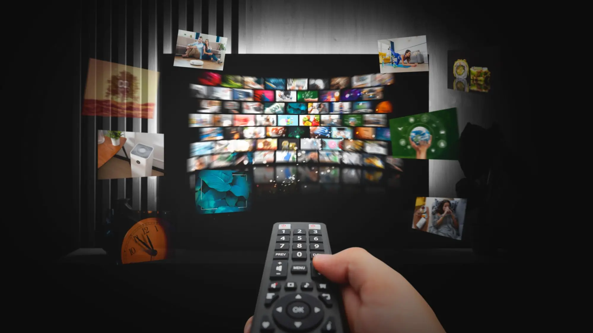 Hand holding a TV remote in front of a wall of live IPTV channels and movies on VOCO TV